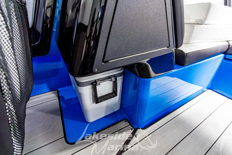 Slide: The Image of 2023 Yamaha Boats 255XE interior with sleek blue and black design, featuring storage compartment. - 28