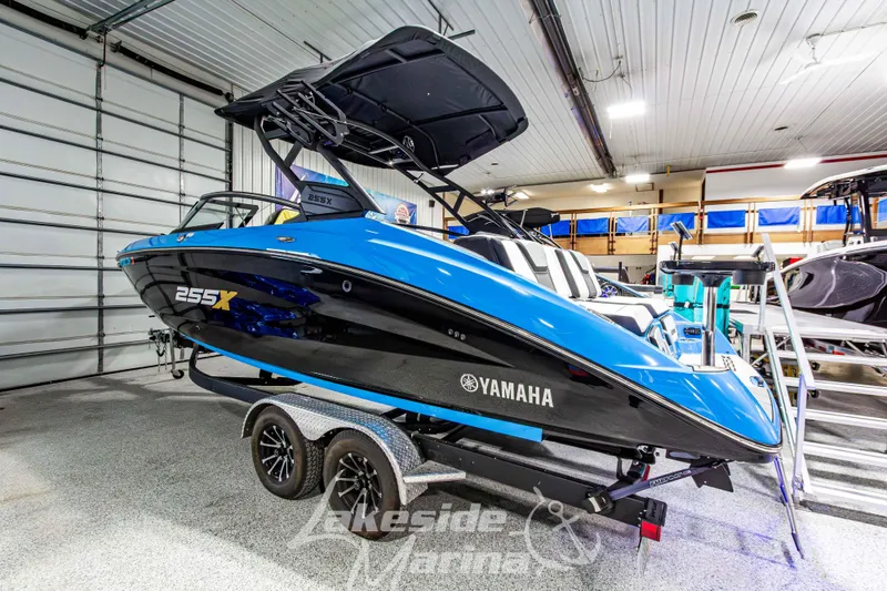 Slide: The Image of 2023 Yamaha Boats 255XE in showroom, blue and black design, on trailer. - 3