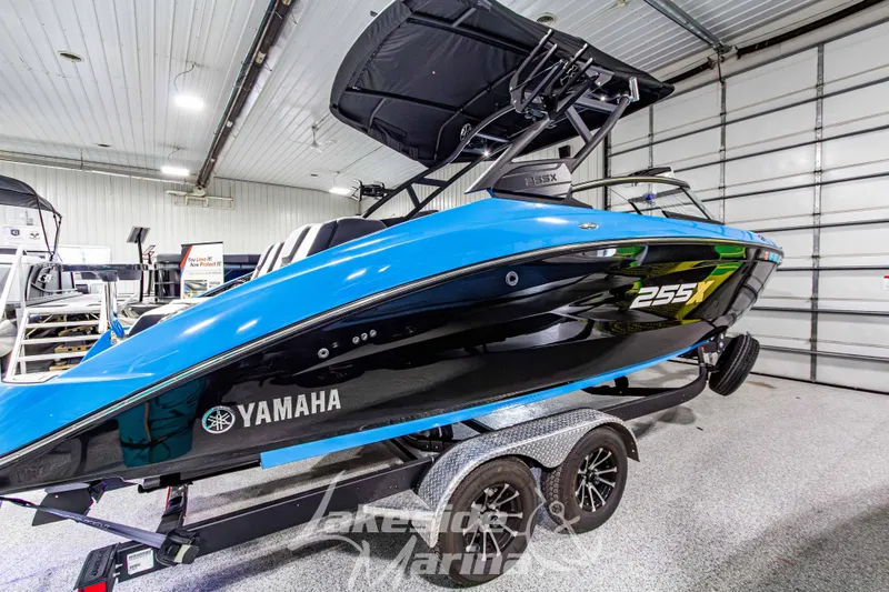 Slide: The Image of 2023 Yamaha Boats 255XE in showroom, blue and black design on trailer. - 6