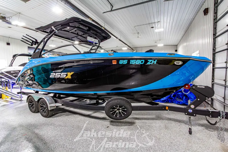 Slide: The Image of 2023 Yamaha Boats 255XE in showroom, blue and black design, on trailer. - 7