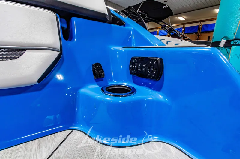 Slide: The Image of 2023 Yamaha Boats 255XE interior with blue panel, control buttons, and cup holder. - 9