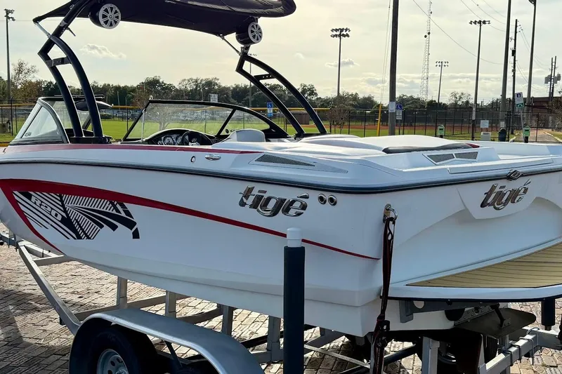 Slide: The Image of 2012 Tigé R20 boat on trailer, parked near sports fields under a clear sky. - 3