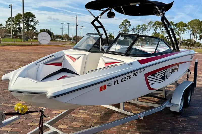 Slide: The Image of 2012 Tigé R20 boat on trailer, white with red accents, parked outdoors. - 4