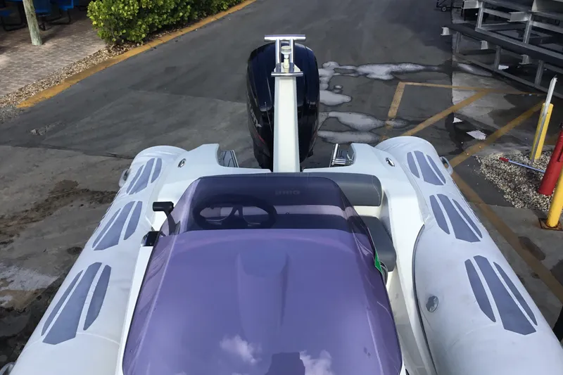 Slide: The Image of 2018 Brig E 480 inflatable boat with purple windshield, parked on a concrete surface. - 13