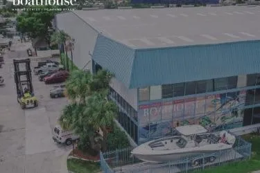 Slide: The Image of Aerial view of a 2018 Brig E 480 boat displayed outside a blue-roofed building. - 16