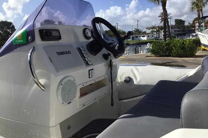 Slide: The Image of 2018 Brig E 480 boat interior with steering wheel and control panel, docked in Florida. - 8