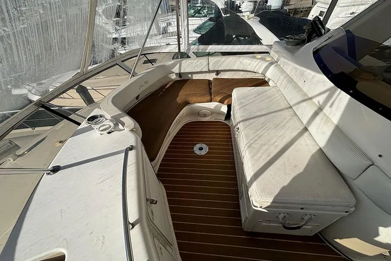 Slide: The Image of 1998 Sea Ray 480 Sedan Bridge interior with cushioned seating and wooden flooring. - 10