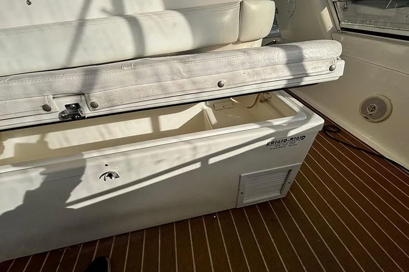 Slide: The Image of 1998 Sea Ray 480 Sedan Bridge interior with open storage compartment and cushioned seating. - 12