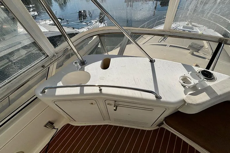 Slide: The Image of 1998 Sea Ray 480 Sedan Bridge helm with controls and seating, overlooking marina. - 13