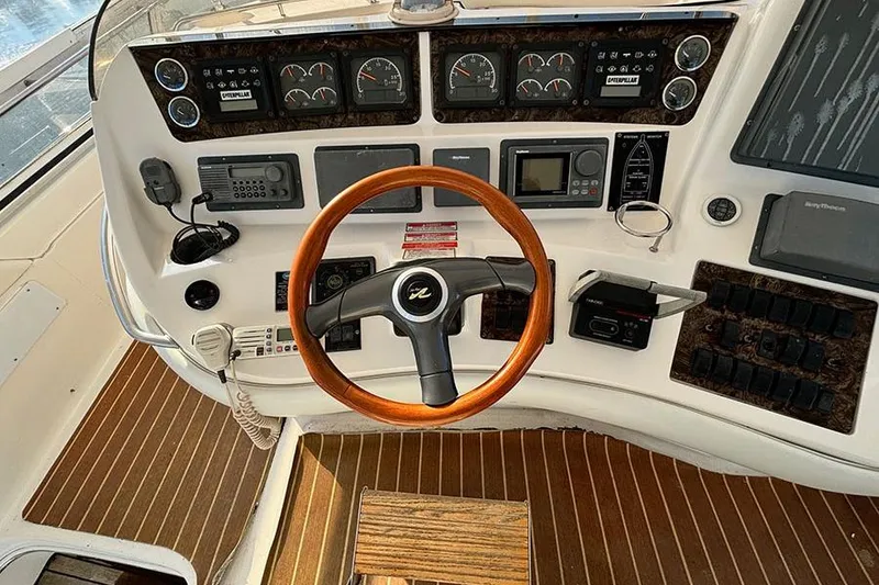 Slide: The Image of 1998 Sea Ray 480 Sedan Bridge helm with wooden steering wheel and navigation instruments. - 16