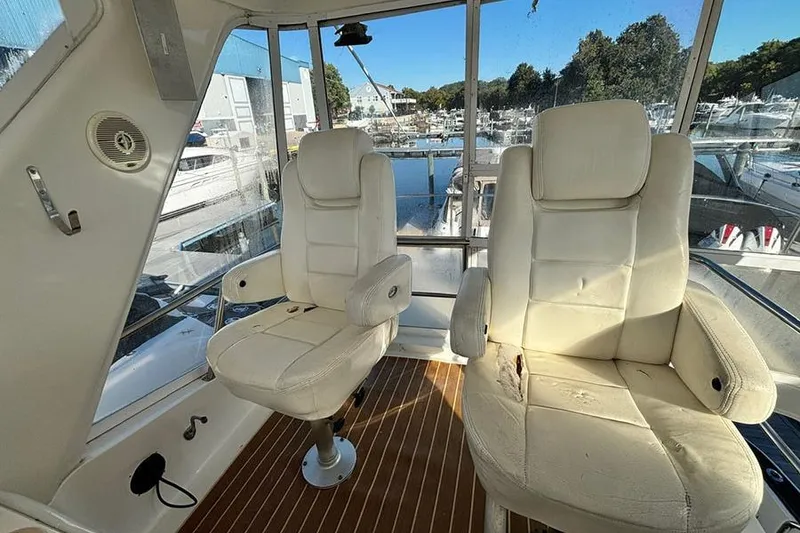 Slide: The Image of 1998 Sea Ray 480 Sedan Bridge interior with two white captain chairs and marina view. - 20