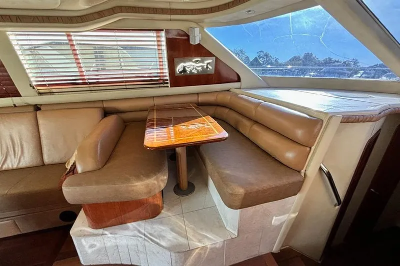 Slide: The Image of 1998 Sea Ray 480 Sedan Bridge interior with leather seating and wooden table. - 25