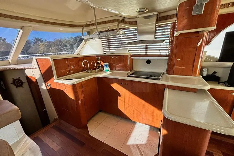 Slide: The Image of Interior of 1998 Sea Ray 480 Sedan Bridge yacht with wooden cabinetry and modern kitchen amenities. - 27