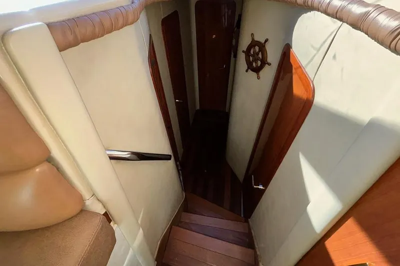 Slide: The Image of 1998 Sea Ray 480 Sedan Bridge interior staircase with wooden accents and nautical decor. - 28