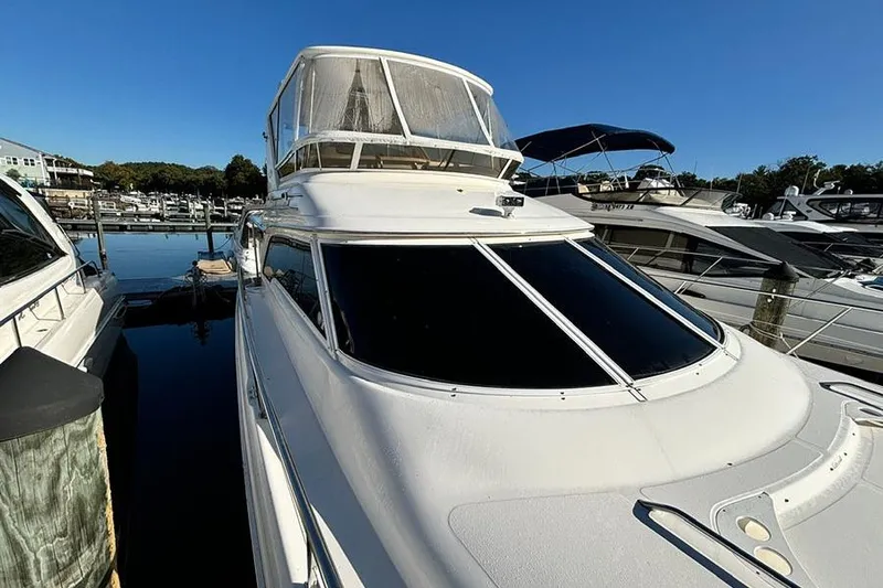Slide: The Image of 1998 Sea Ray 480 Sedan Bridge yacht docked at marina under clear blue sky. - 39