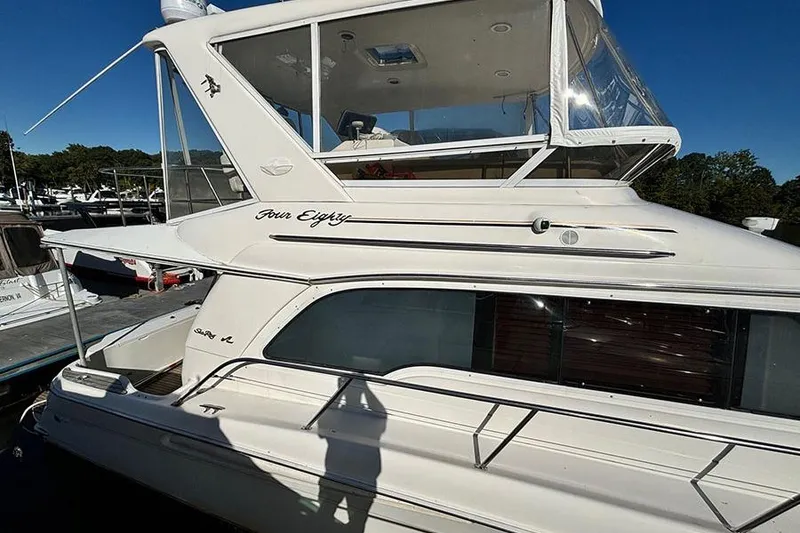 Slide: The Image of 1998 Sea Ray 480 Sedan Bridge yacht docked, showcasing sleek design and upper deck enclosure. - 6
