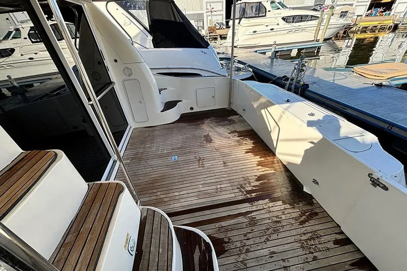 Slide: The Image of 1998 Sea Ray 480 Sedan Bridge yacht deck with wooden flooring and docked boats in background. - 8