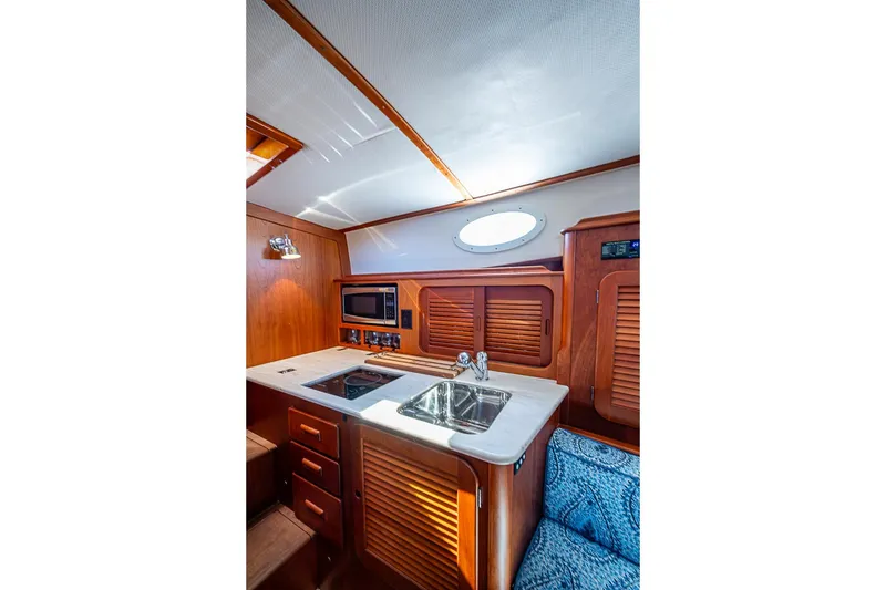 Slide: The Image of 2016 Hinckley Picnic Boat MKIII interior with wooden cabinetry, sink, and microwave. - 14