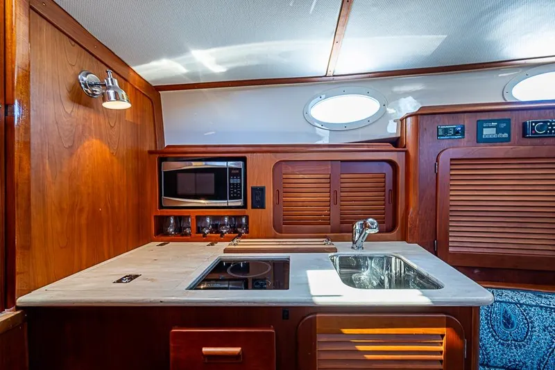 Slide: The Image of 2016 Hinckley Picnic Boat MKIII interior kitchen with wood cabinetry and modern appliances. - 15