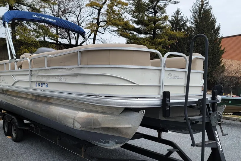 Slide: The Image of 2017 Sun Tracker Party Barge 24 DLX pontoon boat on trailer, parked outdoors. - 2
