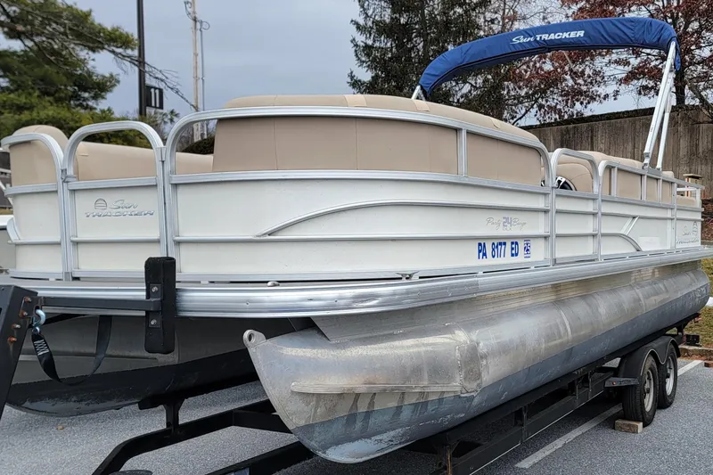 Slide: The Image of 2017 Sun Tracker Party Barge 24 DLX pontoon boat on trailer, beige seating, blue canopy. - 3