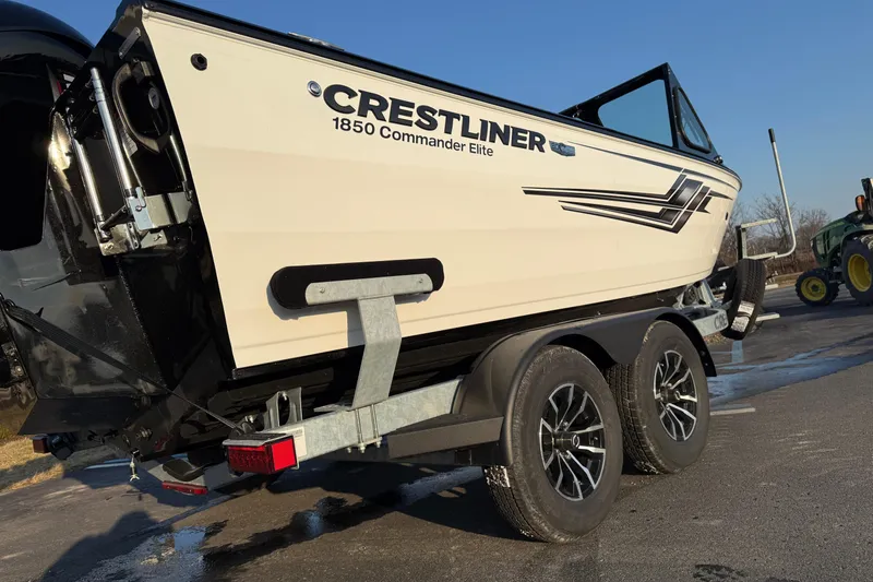 Slide: The Image of 2026 Crestliner 1850 Commander Elite boat on trailer, side view in sunlight. - 2