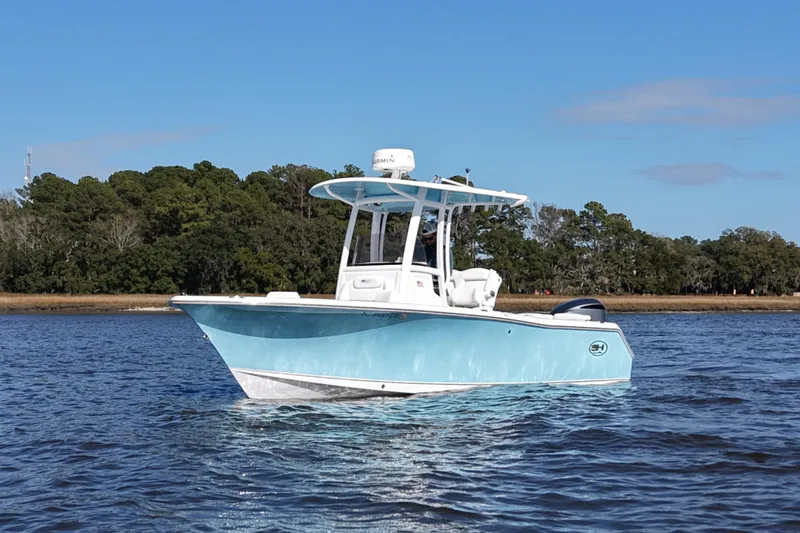 The Image of 2016 Sea Hunt Ultra 235 SE boat on calm water with forested shoreline. - 0