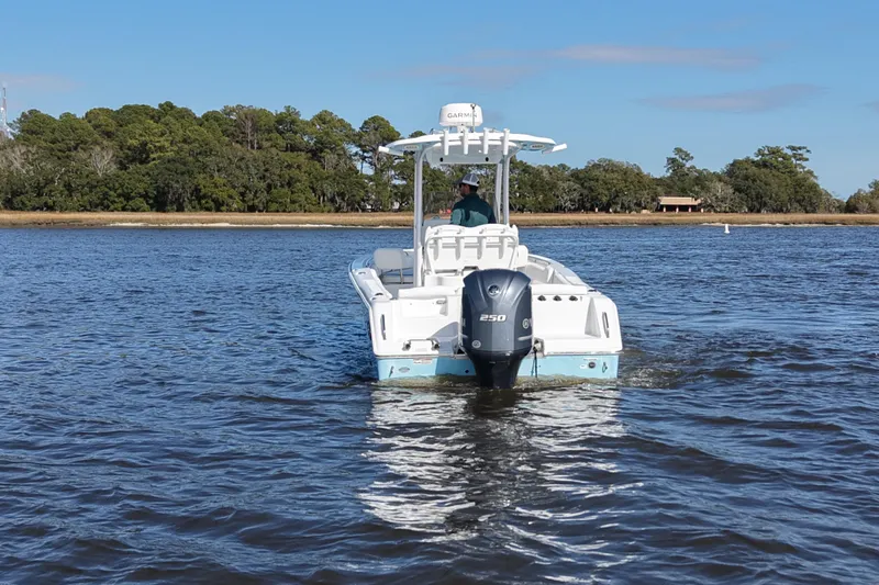 Slide: The Image of 2016 Sea Hunt Ultra 235 SE boat on calm water, with trees in the background. - 3