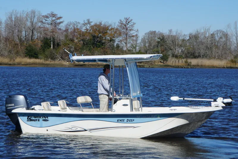 Slide: The Image of 2016 Carolina Skiff 198 DLV boat on calm water with trees in the background. - 14