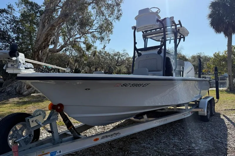 Slide: The Image of 2024 Xplor X24 boat on trailer, parked outdoors under trees. - 3