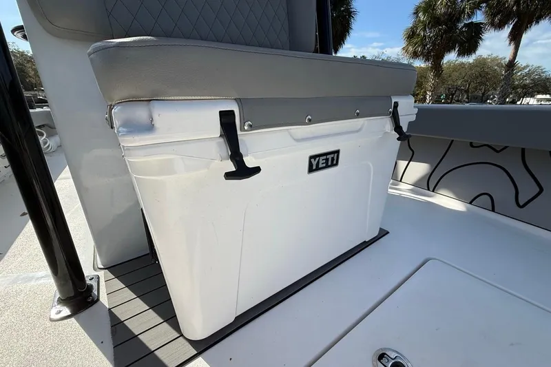 Slide: The Image of YETI cooler on 2024 Xplor X24 boat, featuring cushioned seating and palm trees in the background. - 32