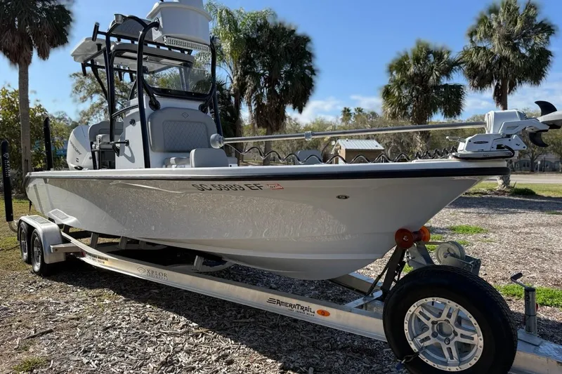 Slide: The Image of 2024 Xplor X24 boat on trailer, parked outdoors with palm trees in background. - 5