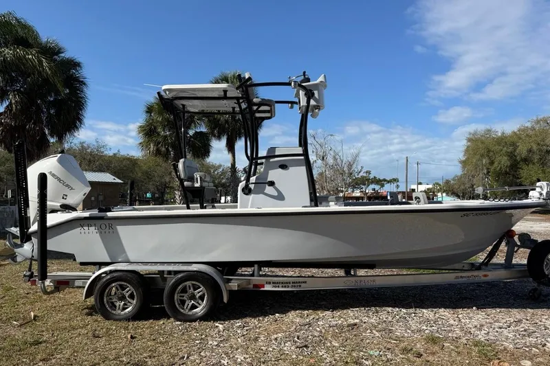 Slide: The Image of 2024 Xplor X24 boat on trailer, parked outdoors with palm trees in background. - 6