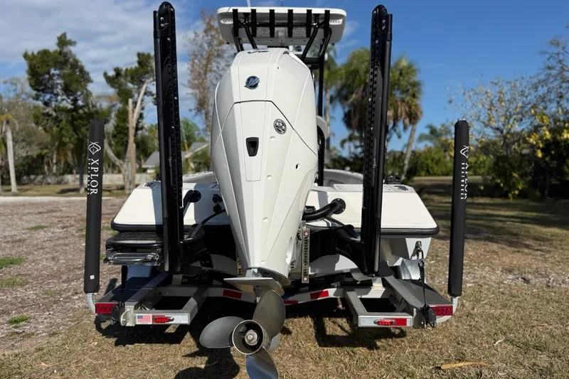 Slide: The Image of 2024 Xplor X24 boat rear view with motor and power poles in a sunny outdoor setting. - 8