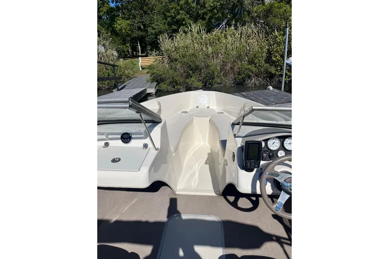 Slide: The Image of 2015 Stingray 191 RX boat interior with dashboard and steering wheel, docked near lush greenery. - 4