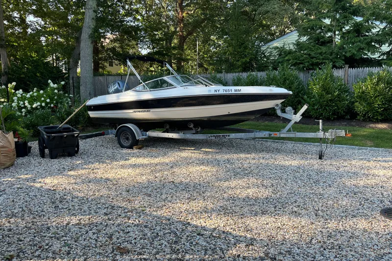 Slide: The Image of 2015 Stingray 191 RX boat on trailer in a gravel driveway, surrounded by greenery. - 7