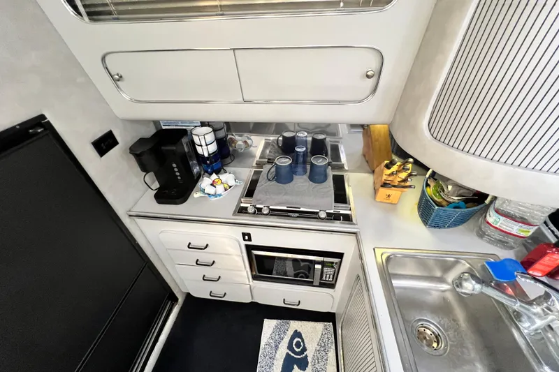 Slide: The Image of Compact kitchen area in a 1987 Chris-Craft 412 Amerosport boat, featuring modern appliances. - 23