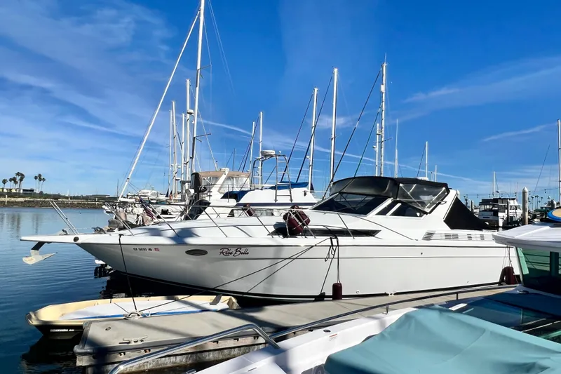 Slide: The Image of 1987 Chris-Craft 412 Amerosport yacht docked in a marina under clear blue skies. - 6
