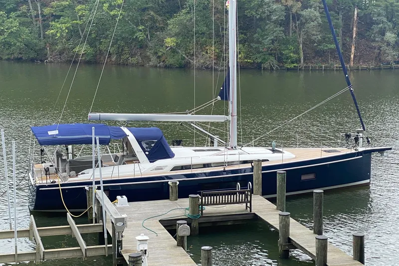 The Image of 2019 Beneteau Oceanis 51.1 sailboat docked on a serene lake with lush greenery. - 0