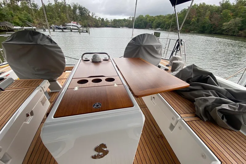 Slide: The Image of 2019 Beneteau Oceanis 51.1 yacht deck with wooden table, docked by a serene lake. - 14
