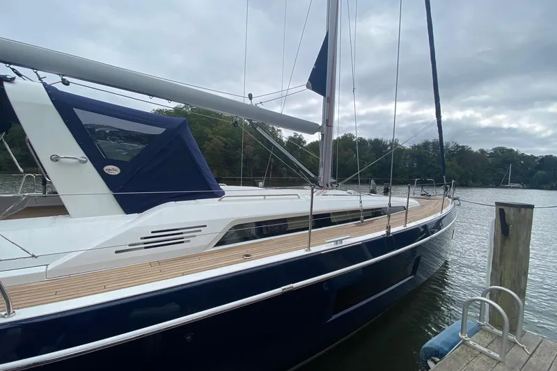Slide: The Image of 2019 Beneteau Oceanis 51.1 sailboat docked on a calm river under cloudy skies. - 7