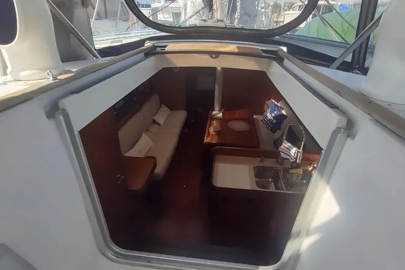 Slide: The Image of Interior view of 1990 Beneteau Oceanis 390 sailboat, featuring cozy seating and compact kitchen area. - 11
