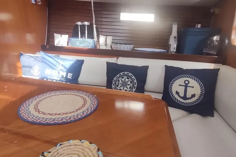 Slide: The Image of Cozy interior of 1990 Beneteau Oceanis 390 with nautical-themed cushions and wooden table. - 12