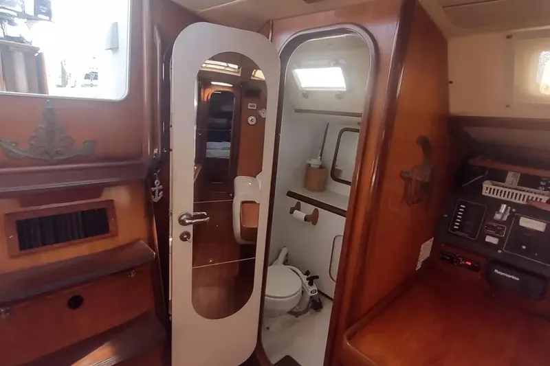 Slide: The Image of Interior of 1990 Beneteau Oceanis 390 sailboat with wooden cabinetry and compact bathroom. - 14