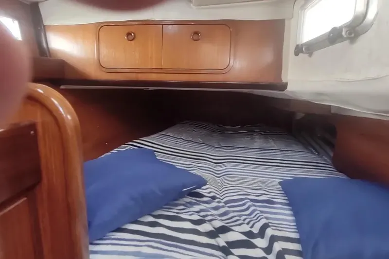 Slide: The Image of Cozy cabin interior of 1990 Beneteau Oceanis 390 with striped bedding and wooden storage. - 21