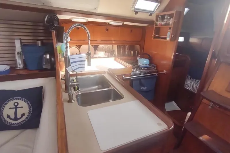 Slide: The Image of Interior of 1990 Beneteau Oceanis 390 yacht kitchen with sink, stove, and wooden cabinetry. - 34
