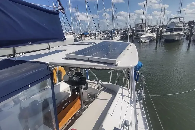 Slide: The Image of 1990 Beneteau Oceanis 390 sailboat with solar panel, docked in a marina under blue skies. - 4