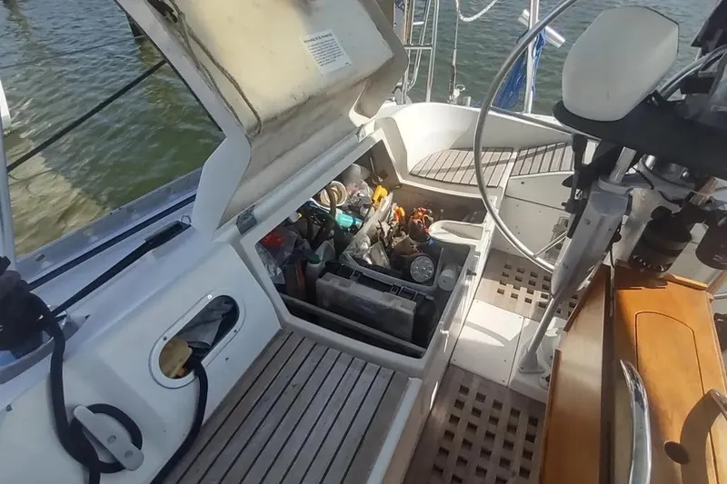 Slide: The Image of Open storage compartment on 1990 Beneteau Oceanis 390 sailboat deck, revealing tools and equipment. - 56