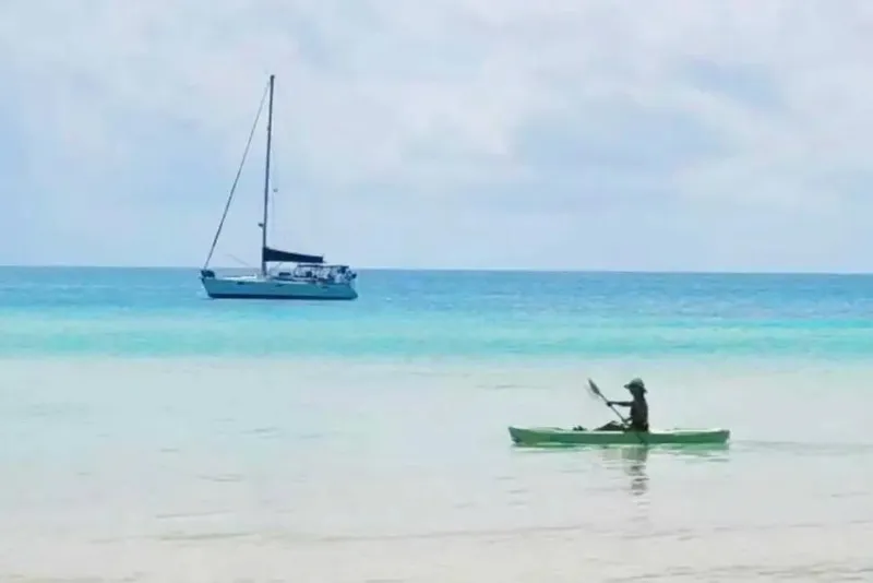 Slide: The Image of Kayaker in calm sea with 1990 Beneteau Oceanis 390 sailboat in the background. - 58