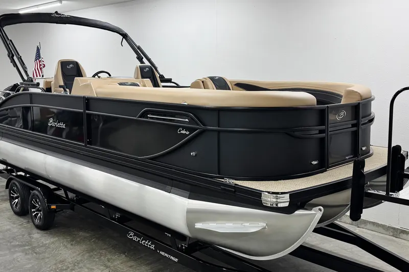 Slide: The Image of 2026 Barletta Cabrio 24UC pontoon boat with sleek black design and tan seating. - 2